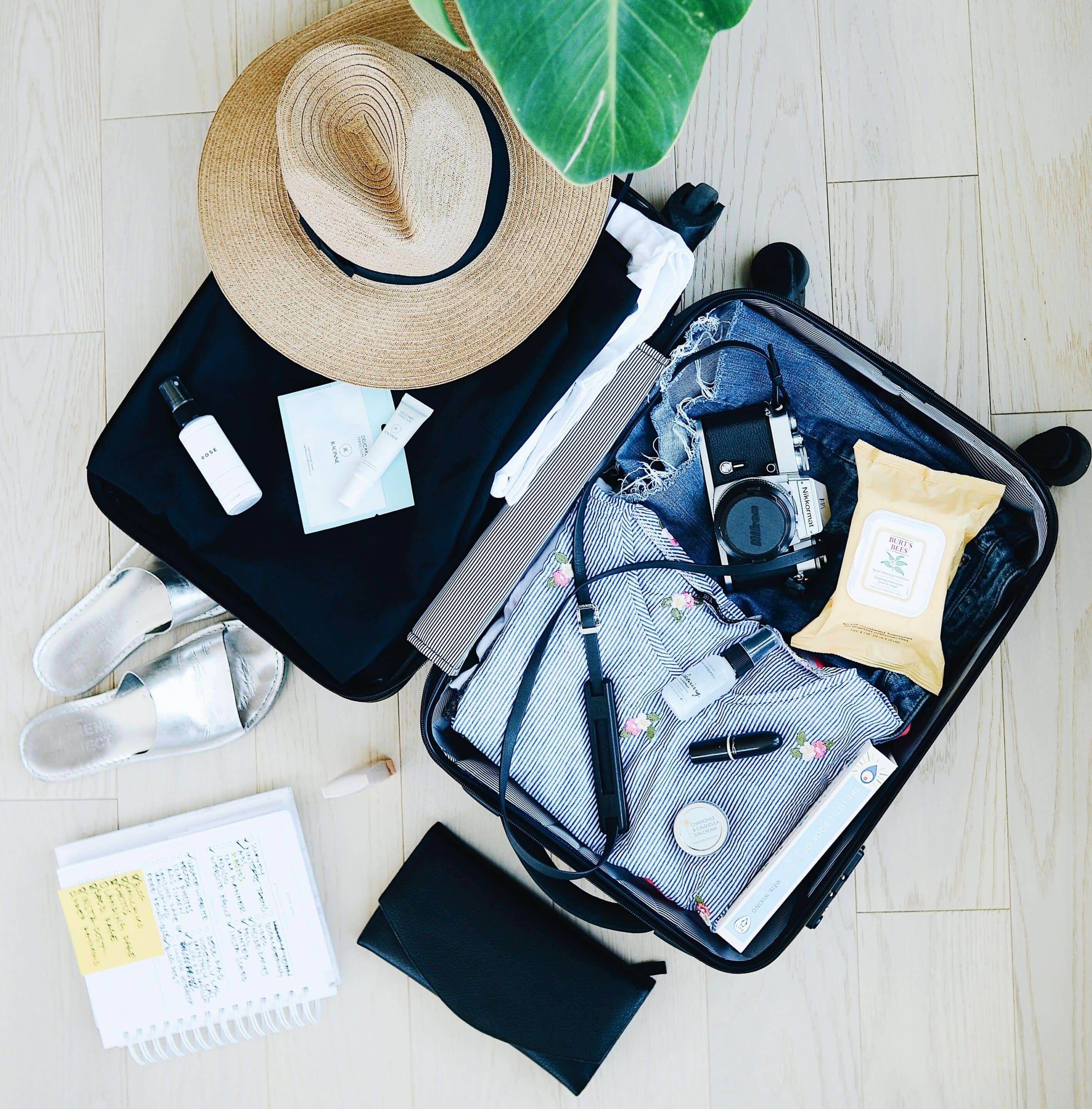 open suitcase containing clothes, hat and camera, things for travelling