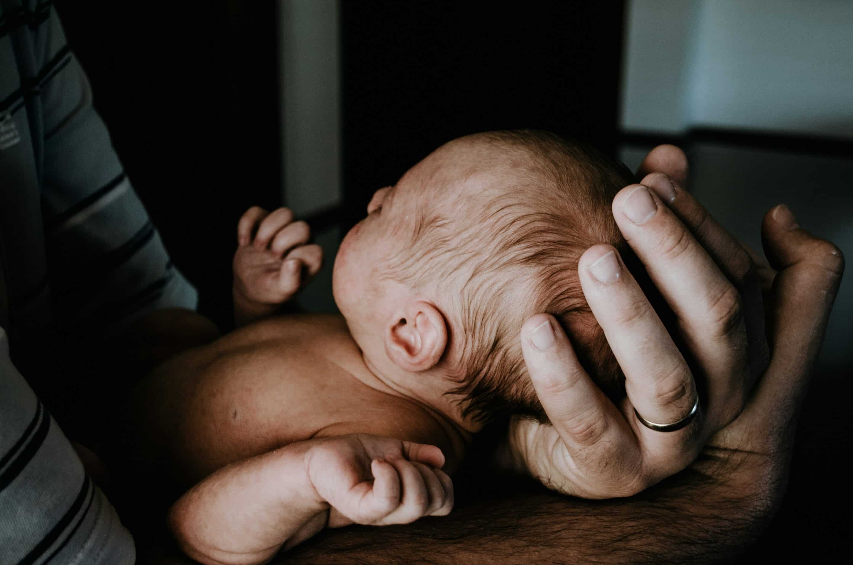 home birth or hospital birth. newborn baby in father's hands